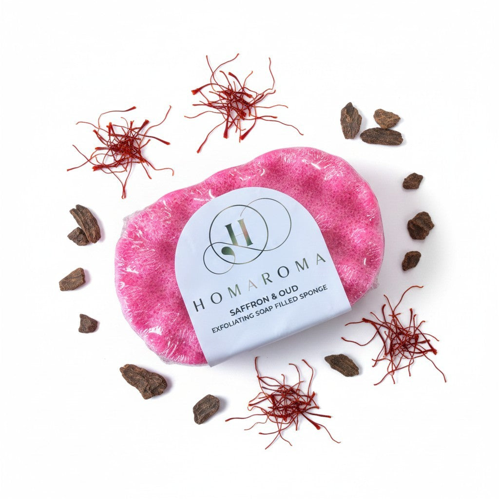 Homaroma Saffron & Oud exfoliating soap-filled sponge in bright pink, surrounded by saffron threads and oud wood pieces.