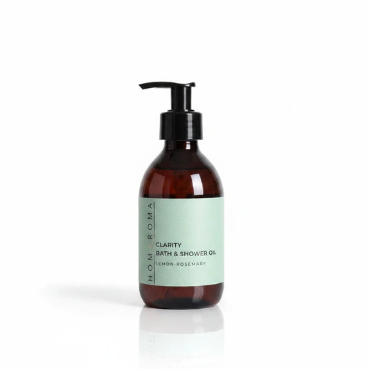 Homaroma Clarity bath and shower oil in an amber glass bottle with a black pump dispenser and light green label.
