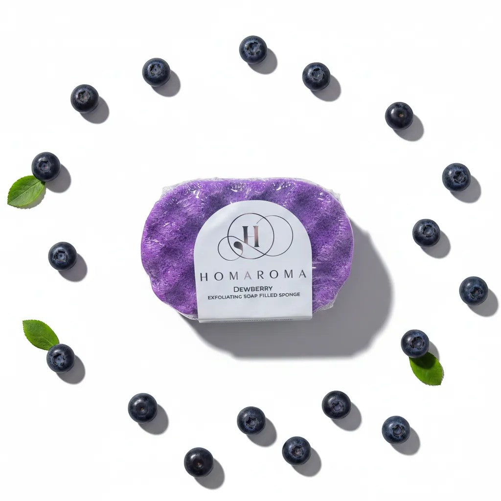 Homaroma Dewberry exfoliating soap-filled sponge in purple, surrounded by fresh blueberries.