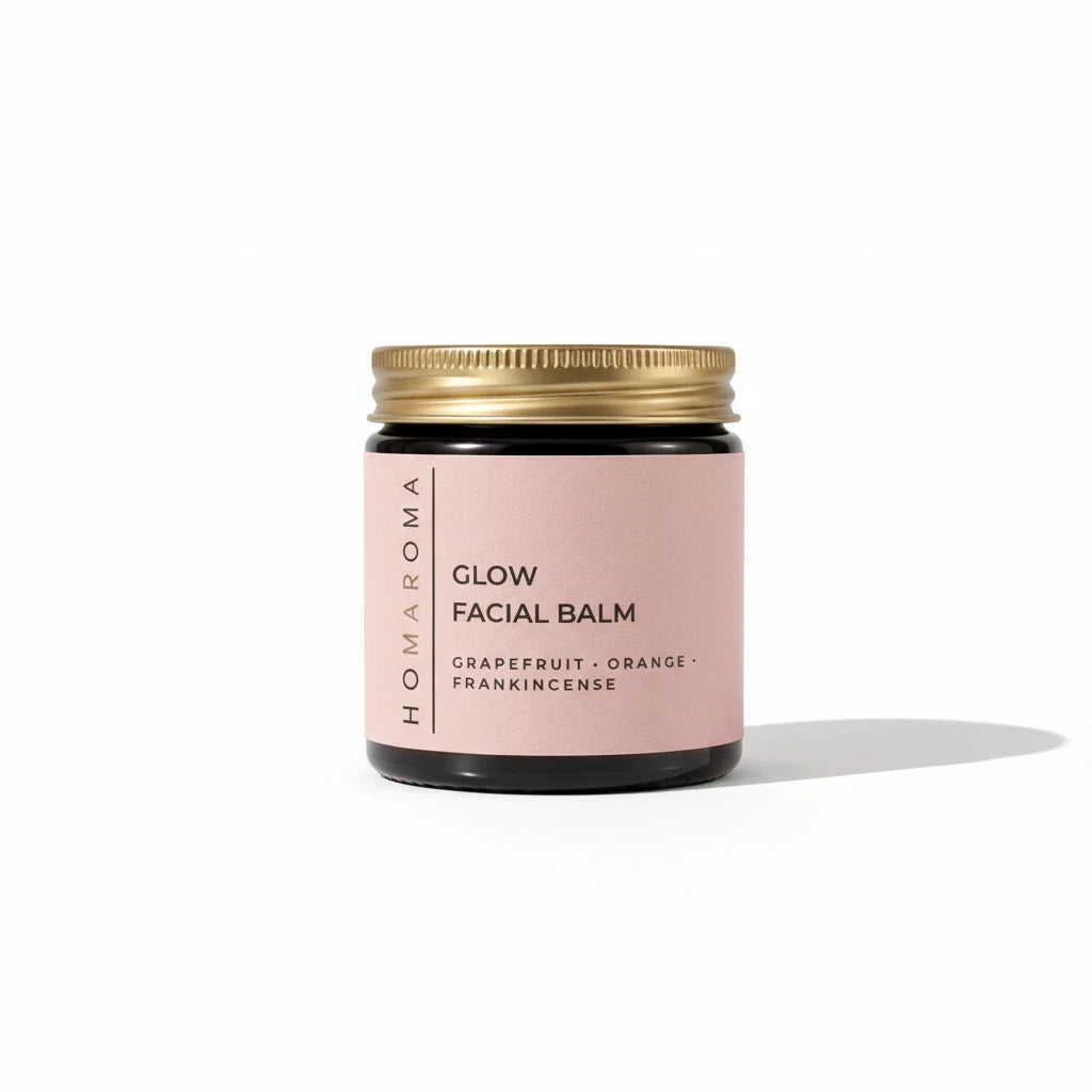 Homaroma facial cleansing balm in a dark glass jar with a gold lid and a soft pink label on a white background.