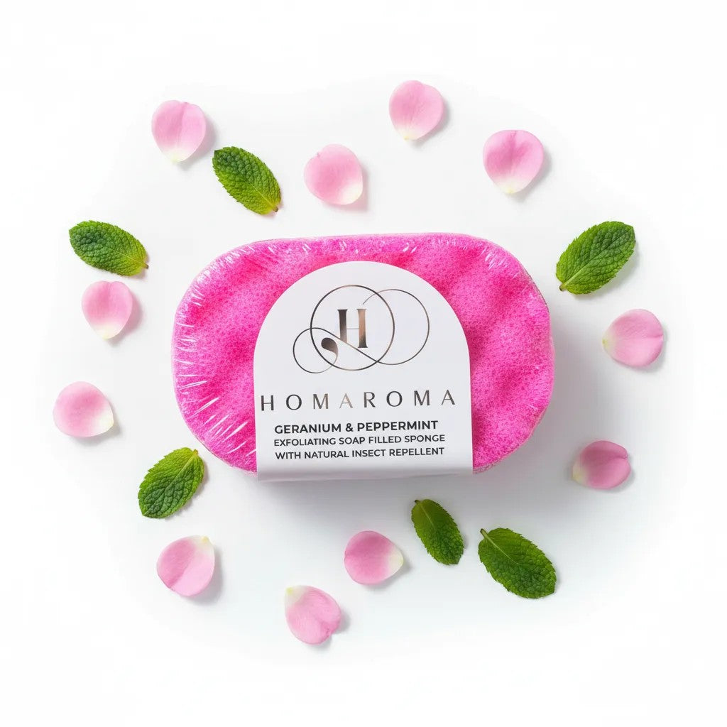 Homaroma pink exfoliating soap-filled sponge with Geranium & Peppermint and natural insect repellent, surrounded by rose petals and mint leaves.