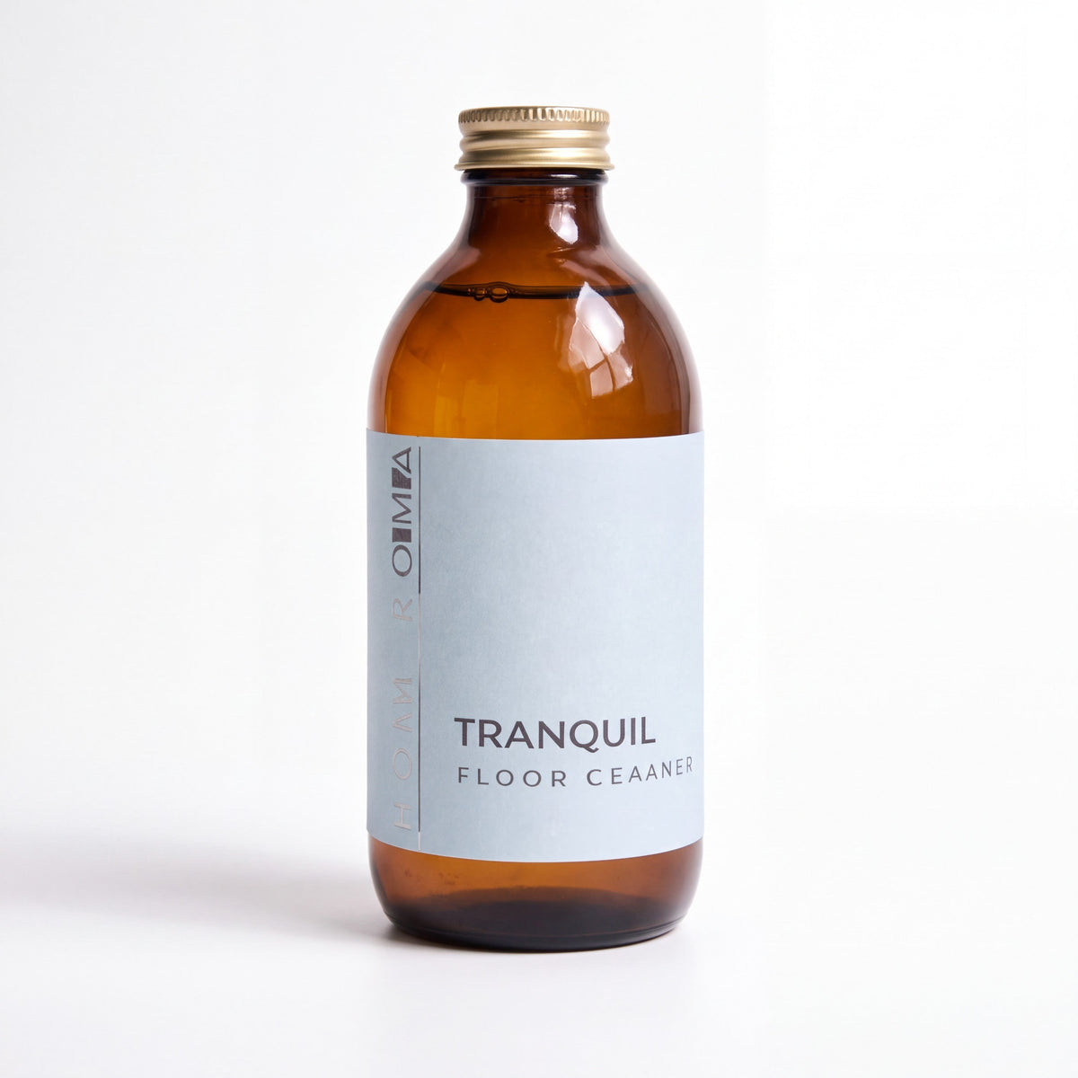 Homaroma Tranquil floor cleaner in an amber glass bottle with a gold cap and light blue label on a white background.
